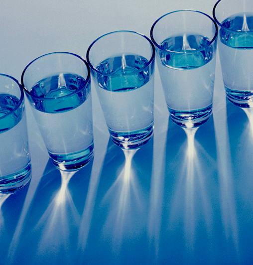 Ein Foto von Gläsern Wasser in einer diagonalen Reihe, von oben gesehen.
