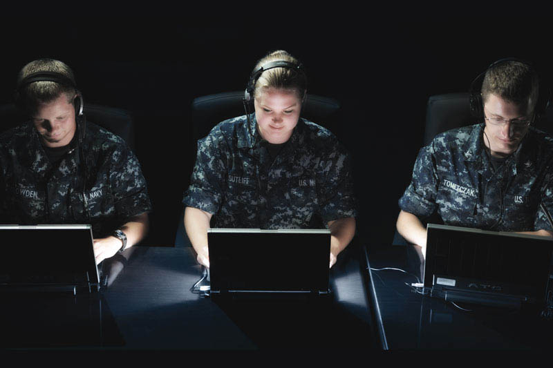 Drei Angehörige der Marine in Uniform, die an Computern arbeiten