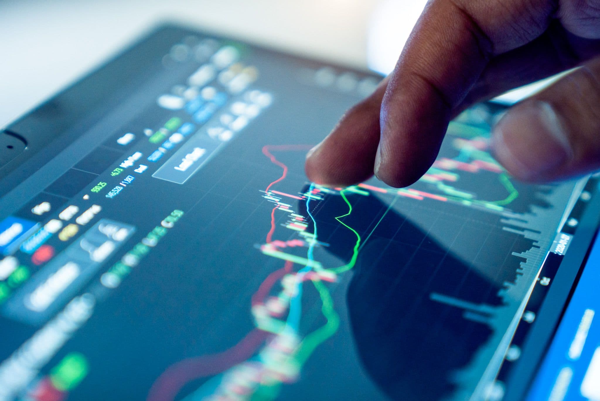 Marktanalyse: Ein Finger zeigt auf Finanzdiagramme auf einem Touchscreen