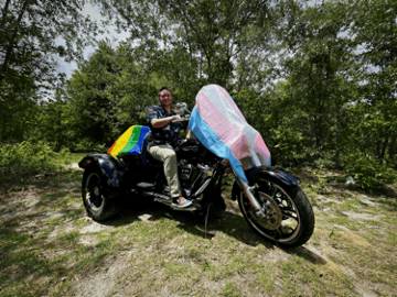 Person auf einem Motorrad mit buntem, im Wind wehendem Stoff