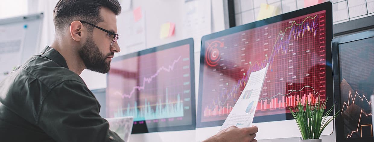 Seitenansicht eines Informationssicherheitsanalysten, der in der Nähe von Diagrammen sitzt