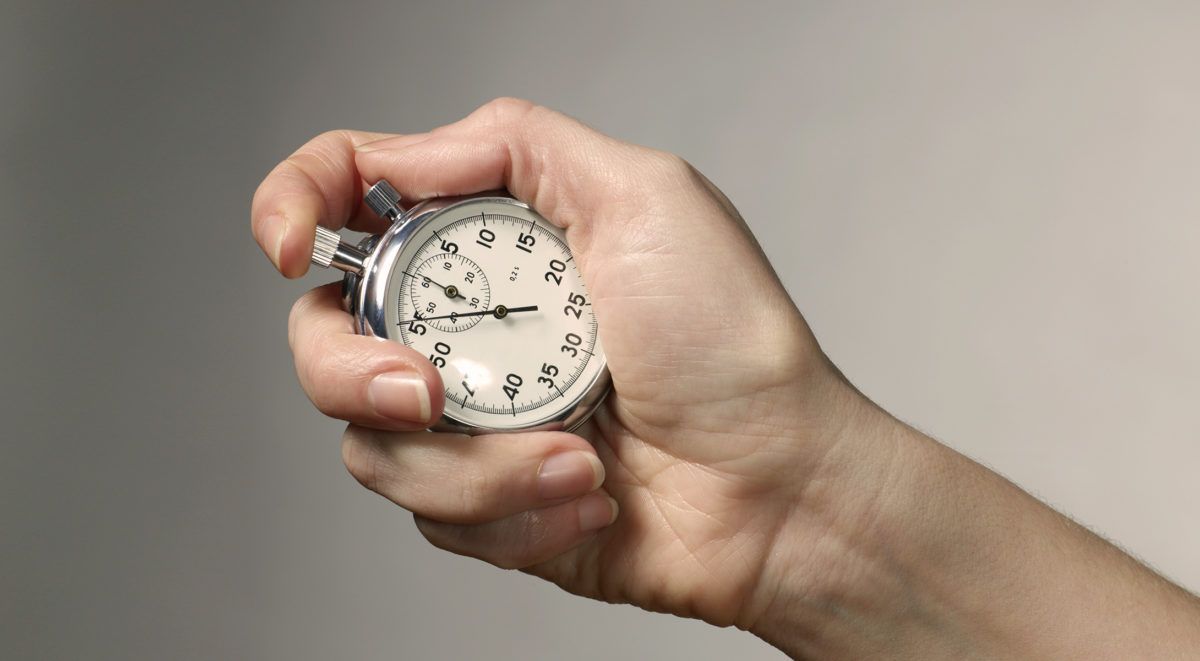 Eine Hand, die eine analoge Stoppuhr hält